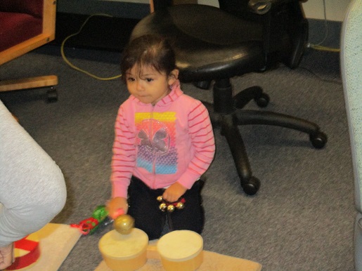 A child is playing with bongos, bells and maracas